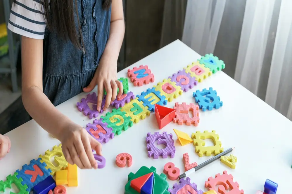 dziewczynka uklada piankowe puzzle